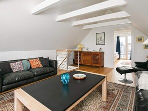 A modern living room with a black sofa, a wooden coffee table, and a patterned rug. - 5 Person Holiday Home in Otterup (Otterup)