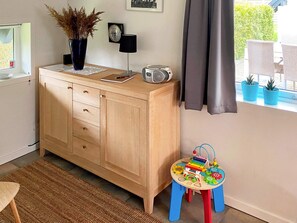 A room with a wooden cabinet, a small table with toys, a radio, and a potted plant. - 5 Person Holiday Home in Otterup (Otterup)