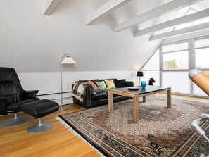 A modern living room with a black leather chair, a black sofa, a wooden coffee table, and a patterned rug. - 5 Person Holiday Home in Otterup (Otterup)