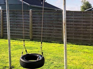 A tire swing suspended by ropes, a wooden fence, and a grassy yard. - 5 Person Holiday Home in Otterup (Otterup)