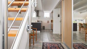 A modern interior with a staircase, a kitchen area, and a dining space.