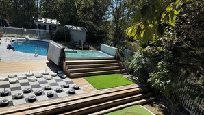 A pool area with a hot tub, a small building, and a mini-golf course.