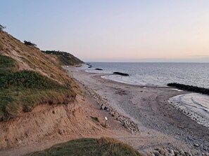 A coastal landscape with a sandy beach, rocky outcrops, and a clear sky. - 5 Star Holiday Home in Vejby (Vejby)