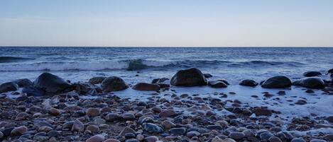 A rocky beach with waves and a clear sky.
