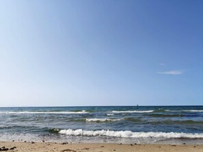 A beach with waves, a clear sky, and a distant sailboat. - 5 Star Holiday Home in Vejby (Vejby)