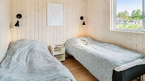 A room with two beds, wooden walls, a window with a view, and a framed picture on the wall. - 5 Star Holiday Home in Vejby (Vejby)