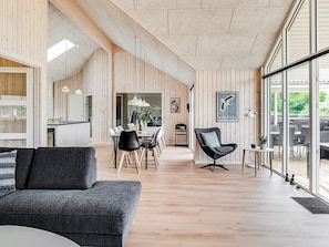A modern interior with a dining area, a sofa, and a view through large windows. - 5 Star Holiday Home in Vejby (Vejby)