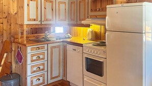 A compact kitchen with wooden cabinets, a sink, a stove, and a refrigerator. - 5 Person Holiday Home in Ringebu (Ringebu)