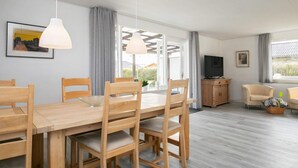 A modern living room with a wooden dining table, chairs, a TV, and a sofa. - 6 Person Holiday Home in Albaek (Aalbaek)