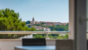 A balcony with a view of a town, including a prominent tower and red-roofed buildings. - Holiday apartment with shared pool (Medulin)