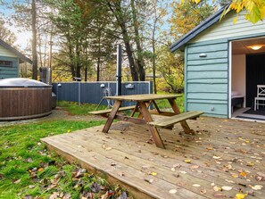 A wooden deck with a picnic table, a hot tub, and a shed in a backyard.