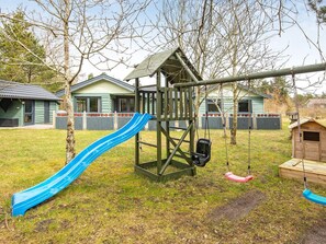 Un parque infantil con tobogán, columpios y una pequeña estructura de madera.