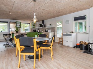 Une cuisine moderne avec un coin repas, un plancher en bois et un luminaire suspendu.