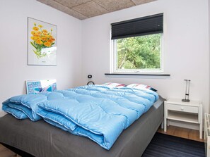 A bedroom with a bed, a window with blinds, a bedside table, and a wall-mounted radiator. - 4 Star Holiday Home in Hemmet (Hemmet)