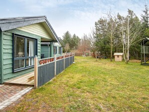 A house with a fenced yard, a small shed, and a swing set.
