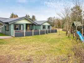 Una hilera de casas de dos pisos con patio cercado y un parque infantil con tobogán.
