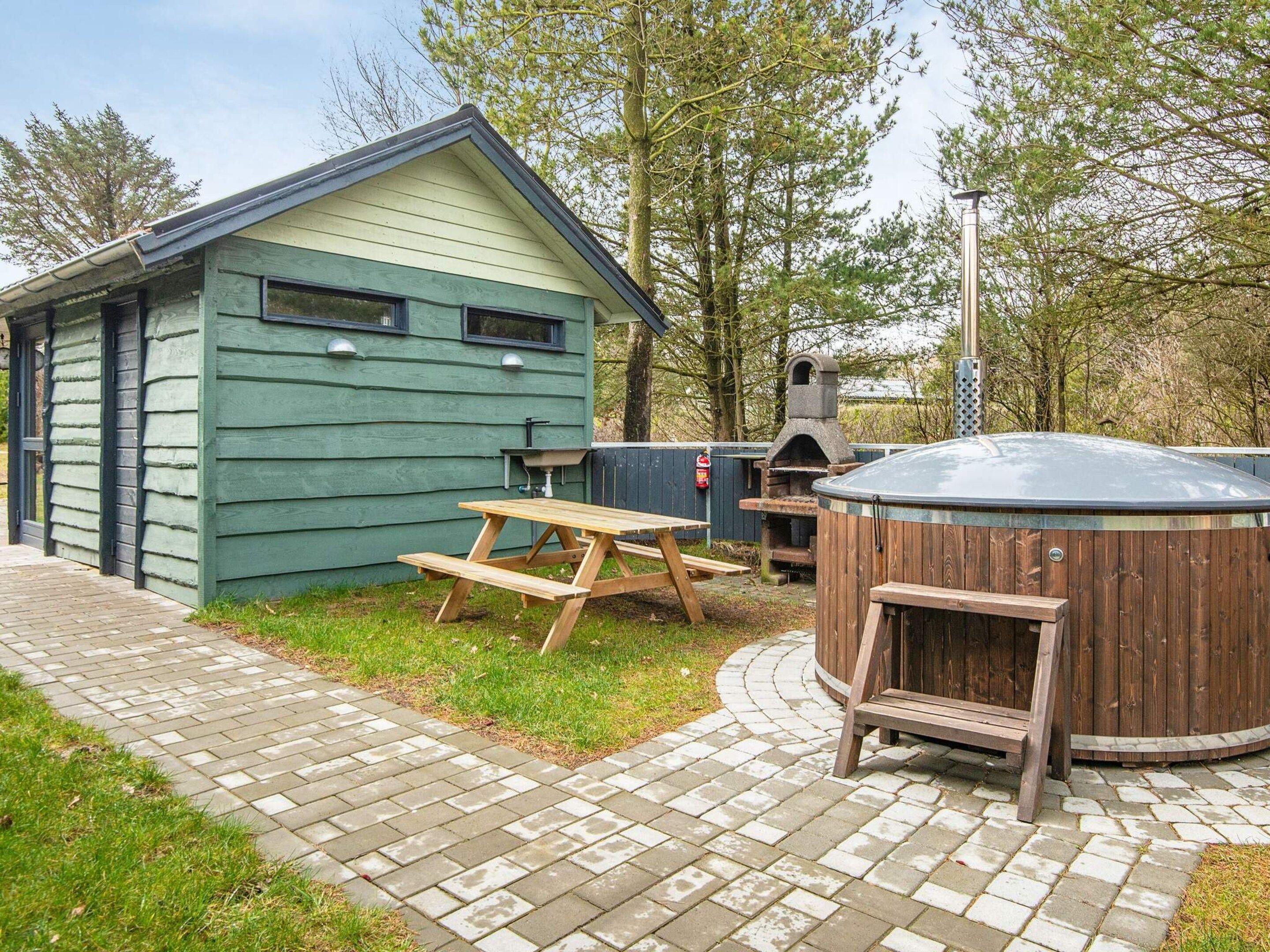 Una cabaña de madera con una mesa de picnic y un jacuzzi.