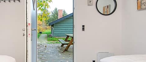 A hotel room with a wooden deck, a bench, a picnic table, a bed, and a wall-mounted mirror.