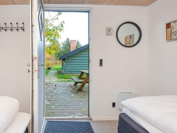 A hotel room with a wooden deck, a bench, a picnic table, a bed, and a wall-mounted mirror.
