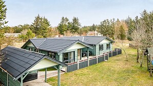 Ein zweistöckiges Haus mit grüner Fassade und einer überdachten Veranda.