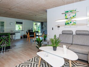 A modern living room with a grey sofa, a white coffee table, and a dining area with a table and chairs. - 4 Star Holiday Home in Hemmet (Hemmet)