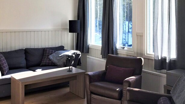 A living room with a sofa, armchairs, a coffee table, and a lamp. - 4 Star Holiday Home in Salen (Salen)