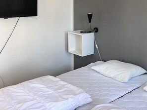 A hotel room with a bed, a bedside table, a wall-mounted TV, and a power outlet. - 4 Star Holiday Home in Salen (Salen)