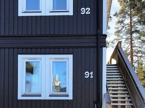 A two-story building with two windows on the upper floor and one on the lower floor, each with white frames.