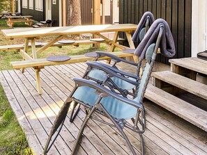 Een houten terras met picknicktafels en een opklapbare stoel.