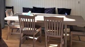 A dining area with a long table, four wooden chairs, and two pendant lights. - 4 Star Holiday Home in Salen (Salen)