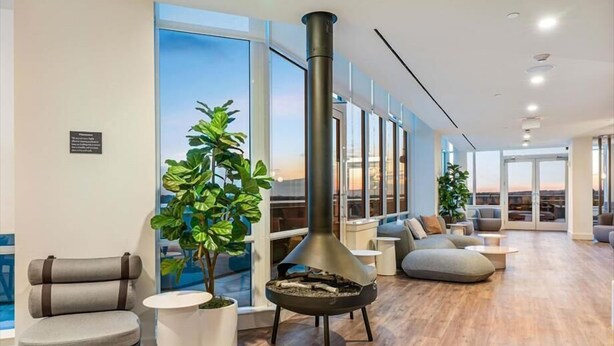 A modern living room with a large fireplace, comfortable seating, and large windows offering a view. - Luxury 1BR in Downtown | Full Kitchen | W&D (White Plains)