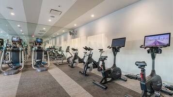 Un gimnasio con diversas máquinas de ejercicio, entre ellas cintas de correr y bicicletas estáticas, dispuestas en filas.