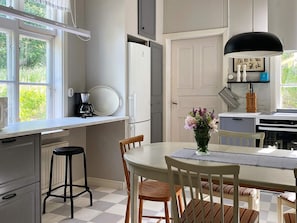 A kitchen with a dining table, chairs, a coffee maker, and a refrigerator. - 4 Star Holiday Home in Sandhem (Sandhem)