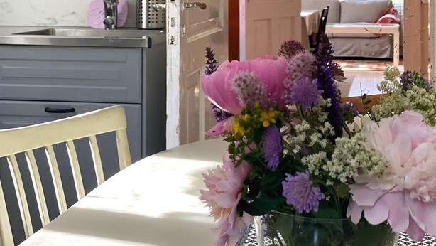 Une cuisine équipée d’un évier, d’une chaise et d’une table agrémentée d’un arrangement floral.