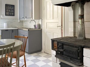 A kitchen with a vintage stove, a sink, and a dining area with a chair.