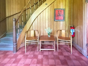 A wooden staircase with a number 16, two wooden chairs, a small table with a vase, and a fire extinguisher on the wall. - 4 Star Holiday Home in Sandhem (Sandhem)