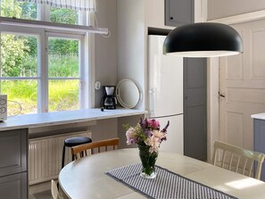 A modern kitchen with a dining table, a coffee maker, and a large window. - 4 Star Holiday Home in Sandhem (Sandhem)