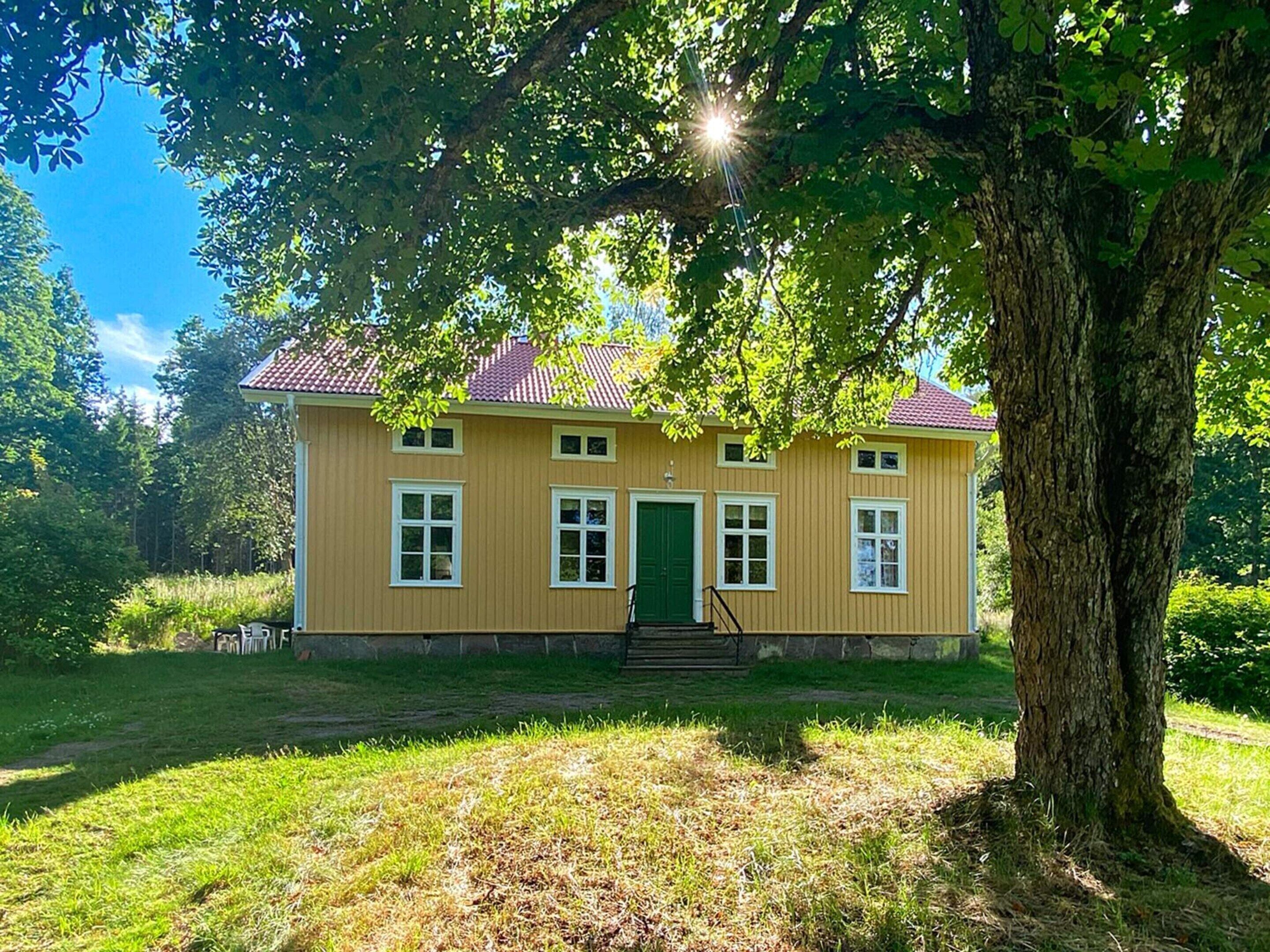 A two-story house with a red-tiled roof, a green door, and white-framed windows.