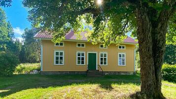 A two-story house with a red-tiled roof, a green door, and white-framed windows.
