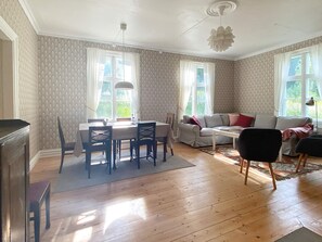 Uma sala de estar com área de jantar, um conjunto de sofá e lareira.