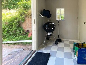 A room with a checkered floor, a small window, a barbecue grill, and a door leading outside. - 4 Star Holiday Home in Sandhem (Sandhem)