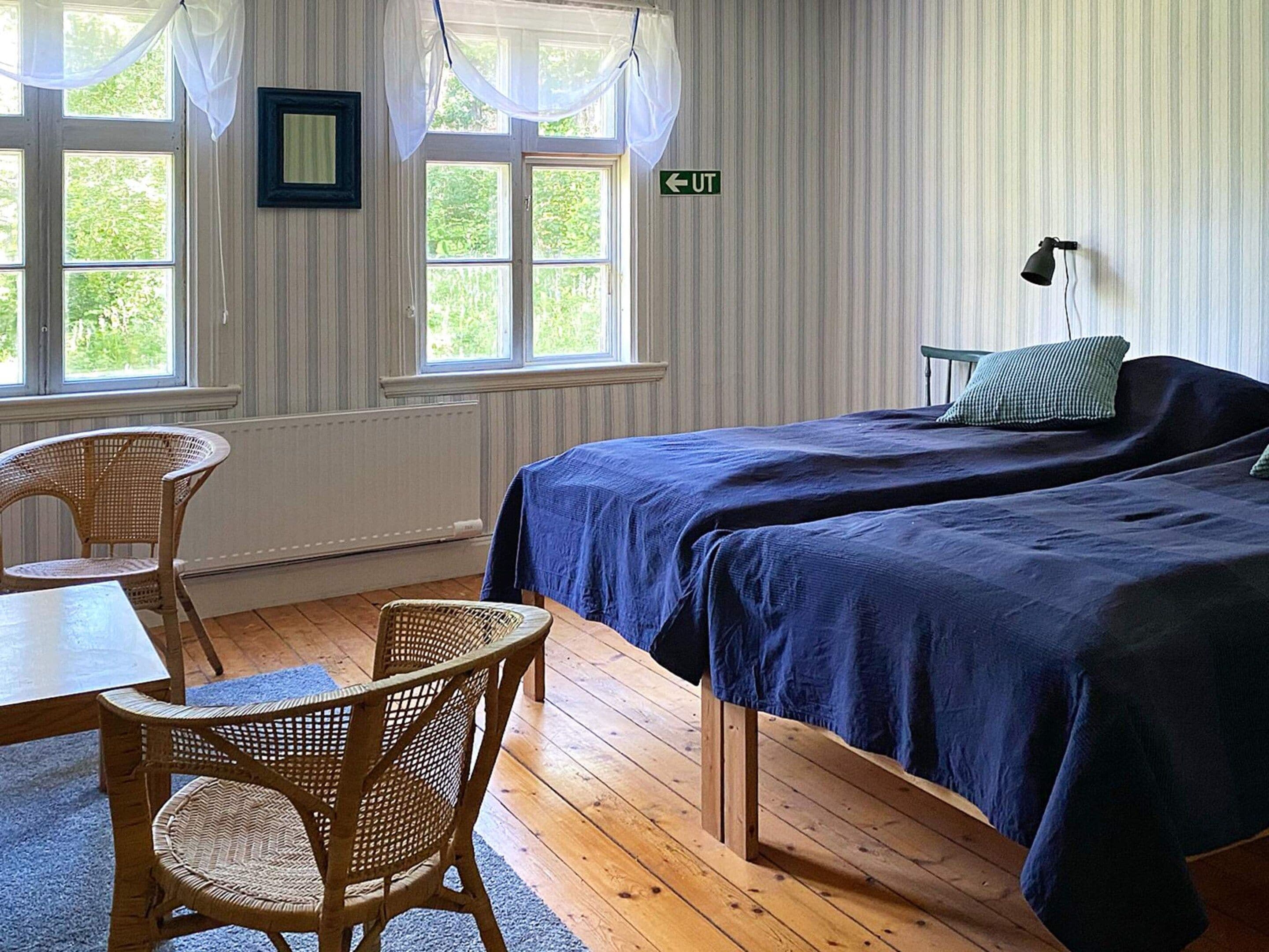 A room with two beds, a table, chairs, and a window with curtains.