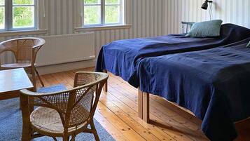 A room with two beds, a table, chairs, and a window with curtains.