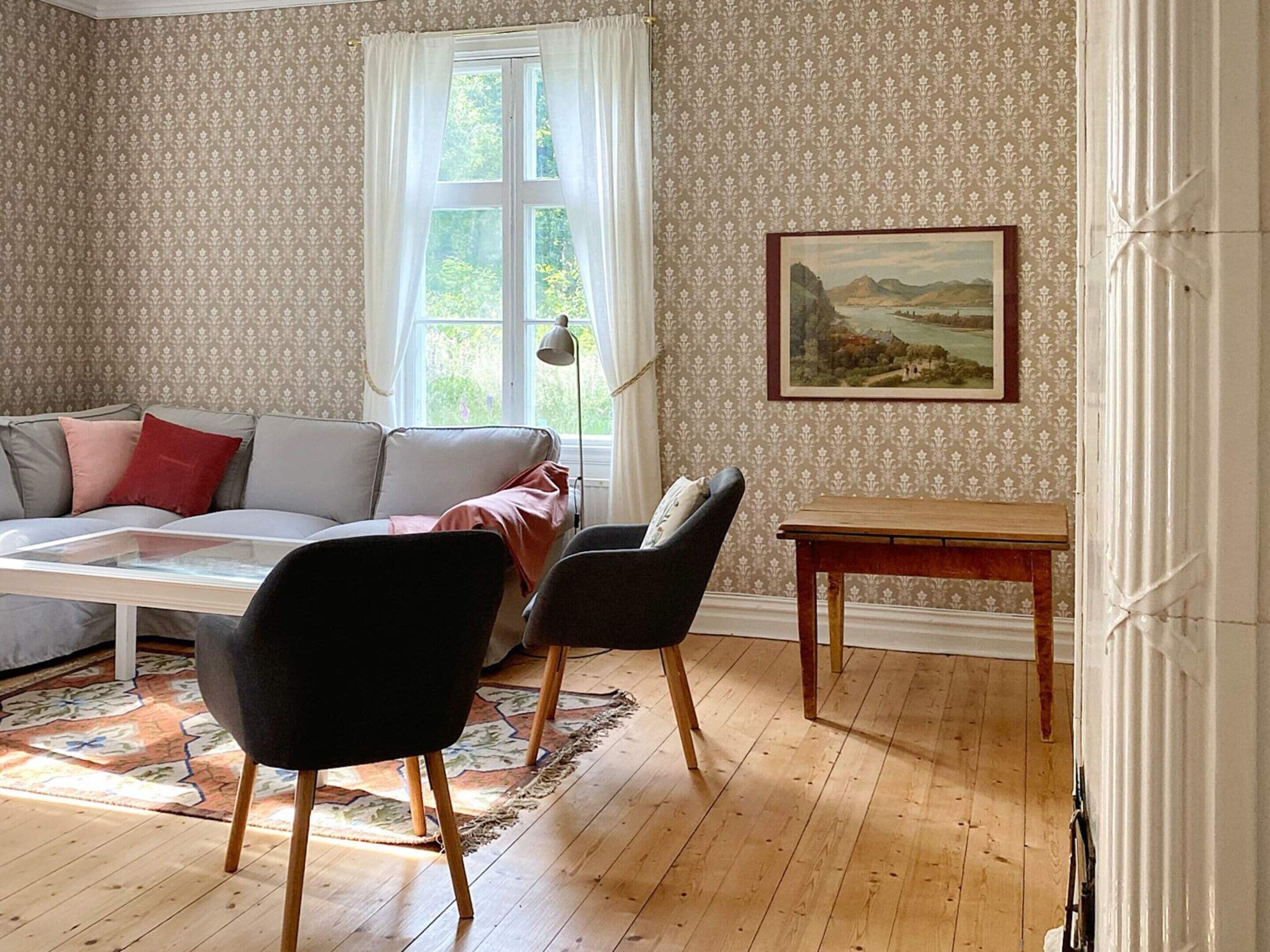 Una sala de estar con un sofá, dos sillones, una mesa de centro, una lámpara y un cuadro en la pared.