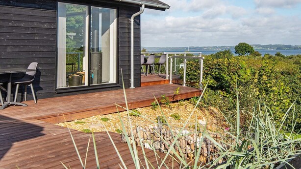 Une maison moderne dotée d’une terrasse en bois, de grandes portes-fenêtres coulissantes et d’une vue sur la mer.