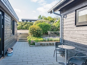 A patio area with a table and chairs, a stone staircase, and a garden with various plants. - 8 Person Holiday Home in Borkop-by Traum (Borkop)