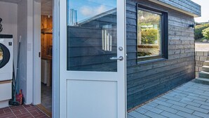 Un bâtiment moderne avec une façade en bois foncé, une porte blanche dotée d’un panneau de verre et une petite fenêtre.