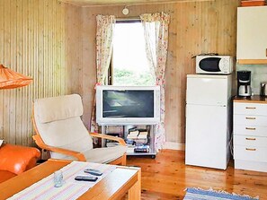 Cozy living space with a television, refrigerator, and kitchenette, perfect for a compact stay.