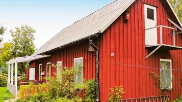 Standalone barn with a small porch and lush surroundings.