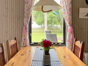 A wooden dining table with a vase of flowers, a striped placemat, and wicker chairs. - 4 Person Holiday Home in Hogklint (Visby)